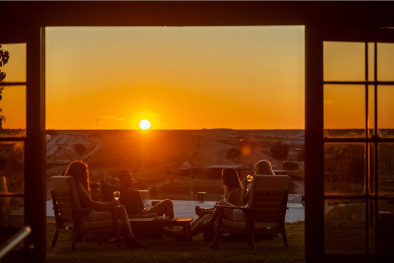 A group of friends enjoy happy hour as the sun sets over Coober Pedy.